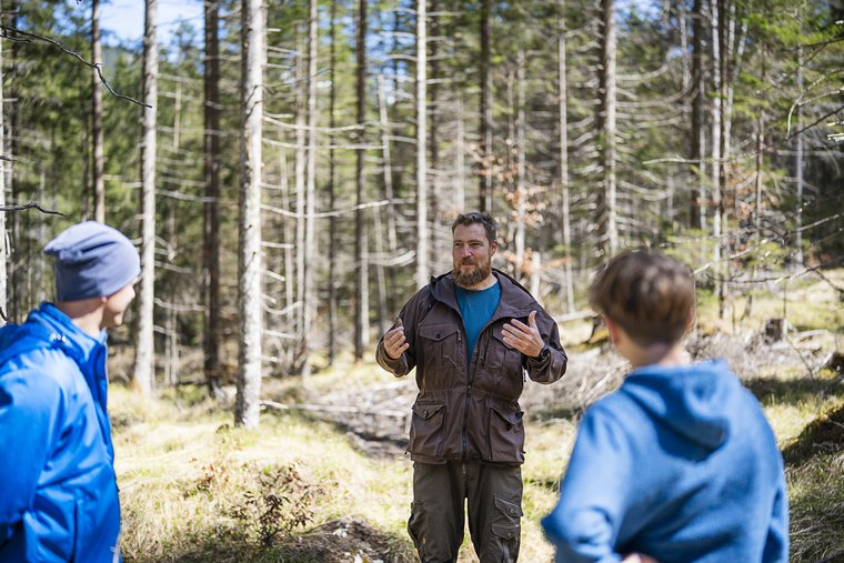 Drei Personen im Wald sprechen miteinander